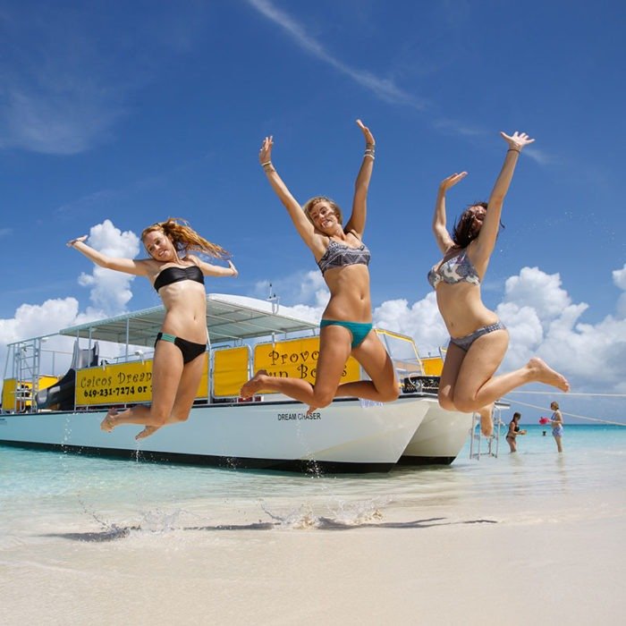 friends jumping in front of caicos dream tour boat