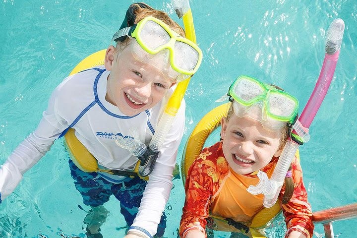 Two children in snorkeling gear smiling in a pool.