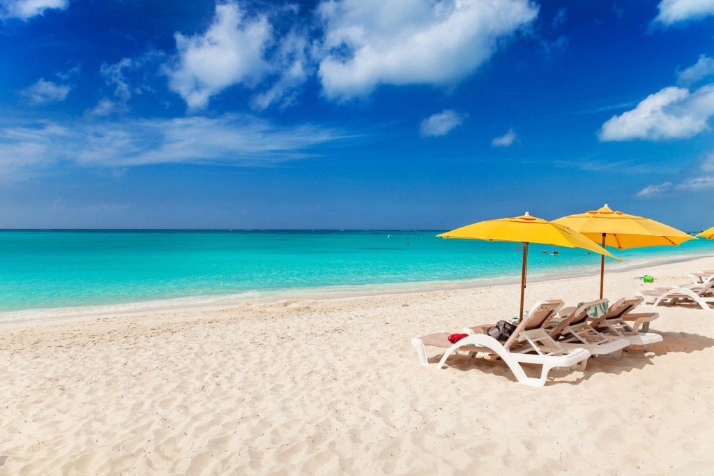 Sunny beach with yellow umbrellas and loungers by the turquoise ocean.