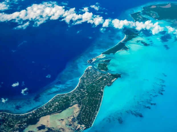 Aerial view of a tropical island with clear blue waters and green land.