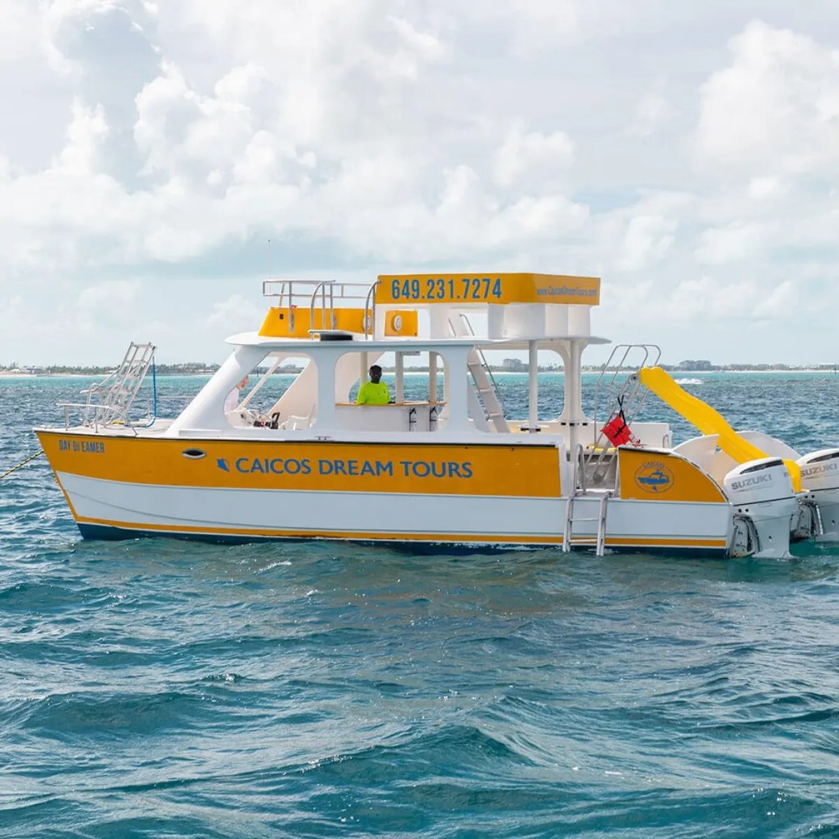 Yellow and white boat on the water with a cloudy sky background.