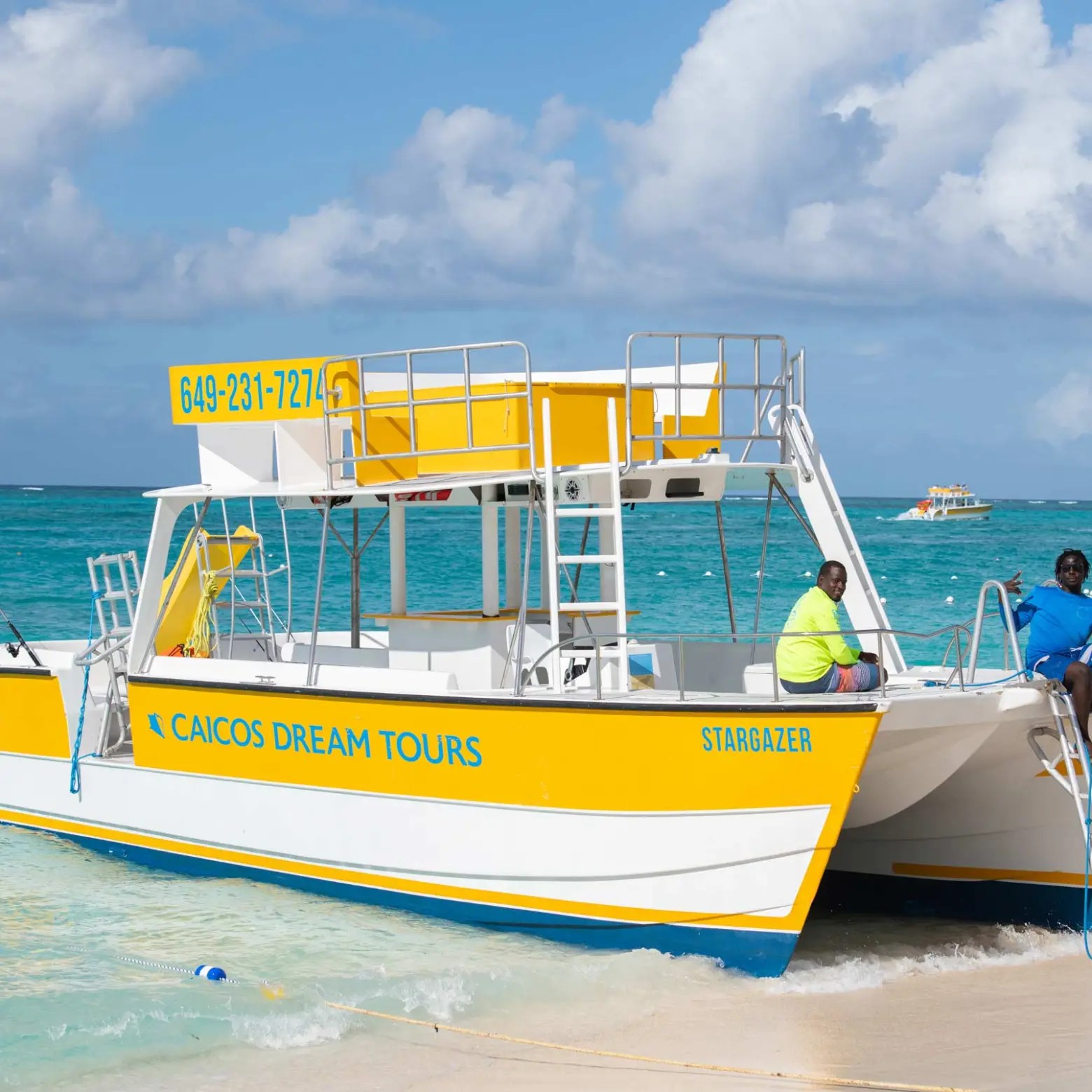Tour boat named Stargazer docked on a sandy beach with two people onboard.