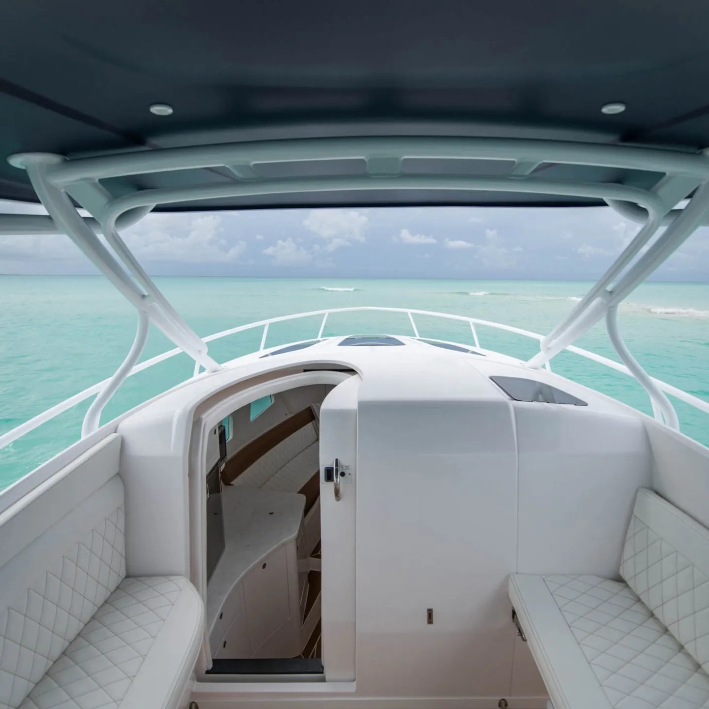 View from yacht helm over turquoise sea under cloudy sky.