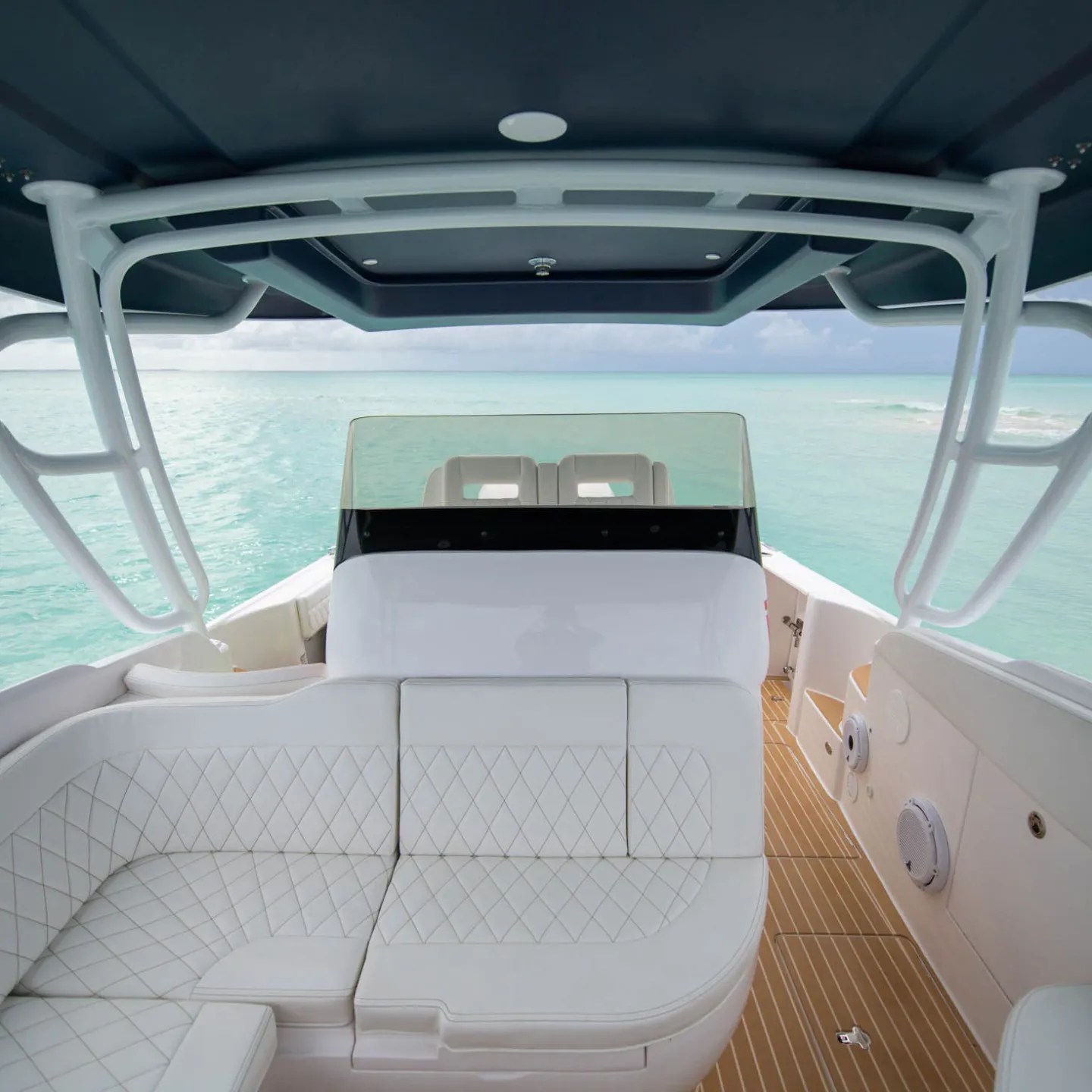 Interior of a boat with white seating, clear ocean view, and blue sky.