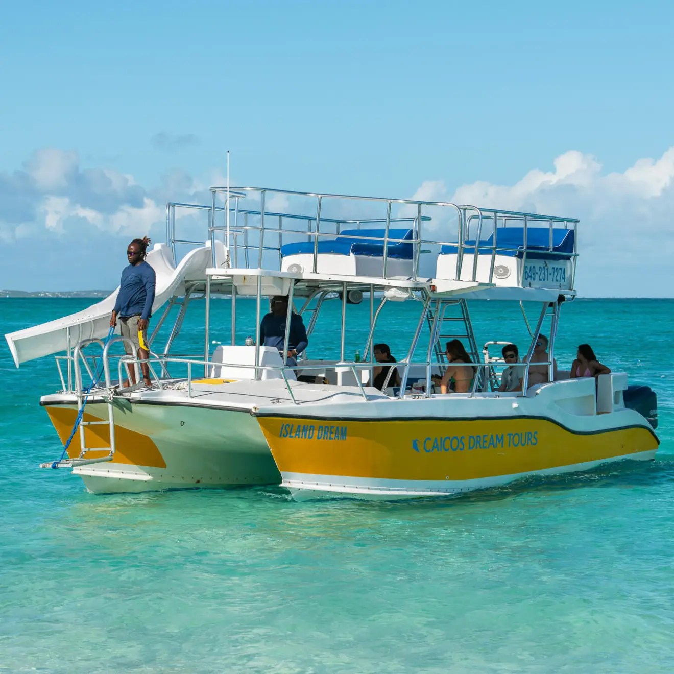 Tour boat on turquoise water with passengers and a guide on deck.