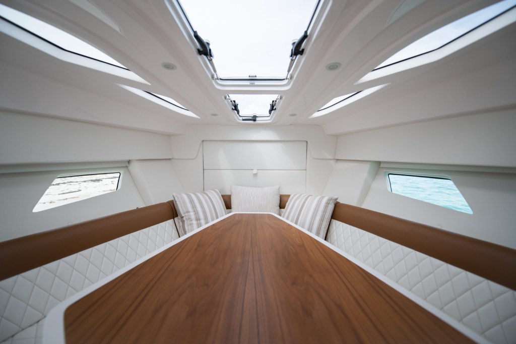 Interior of a yacht cabin with a wood table and cushioned seating.