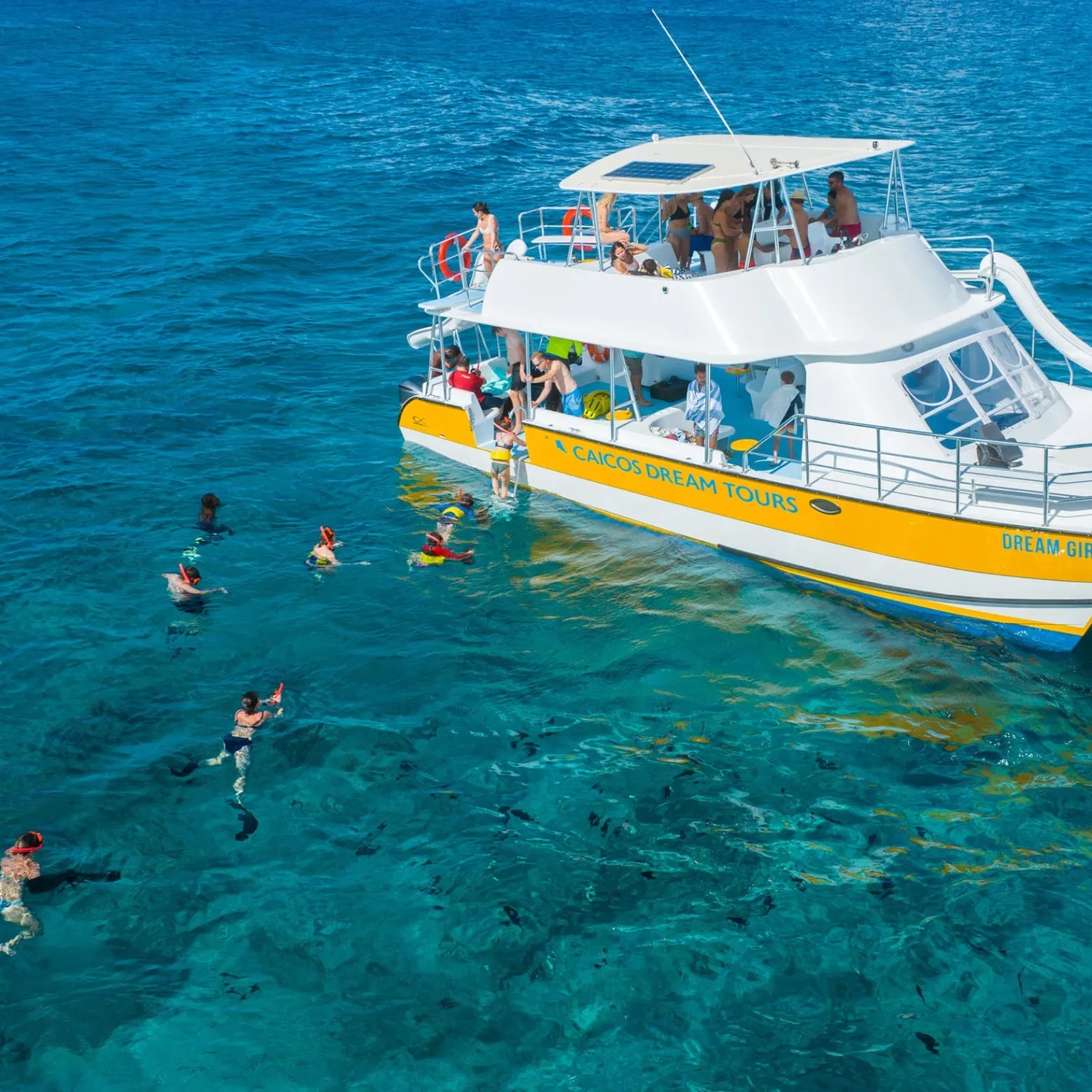 Boat with tourists snorkeling in clear blue ocean waters.