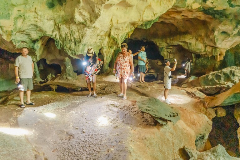 People exploring a dimly lit cave with flashlights.