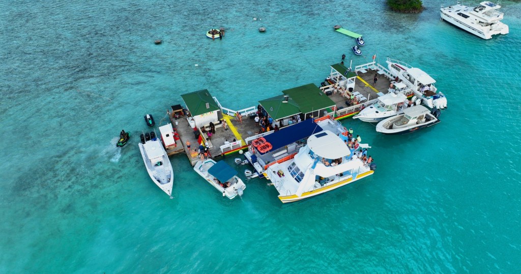 Boats connected on turquoise water forming a floating platform scene.