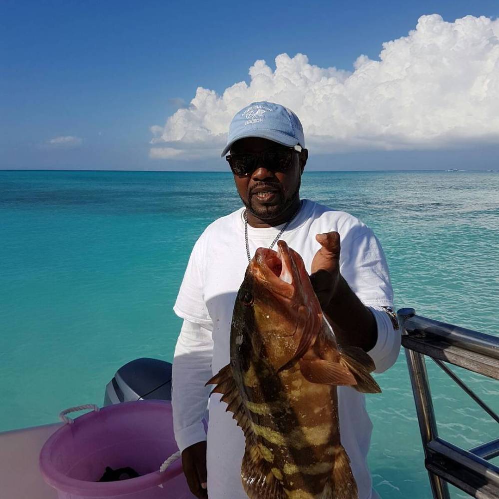 a person holding a fish in front of a body of water