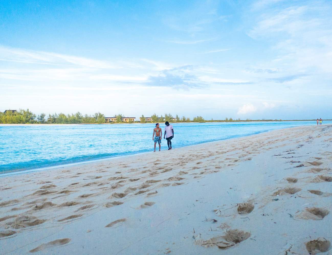 a group of people standing on top of a sandy beach