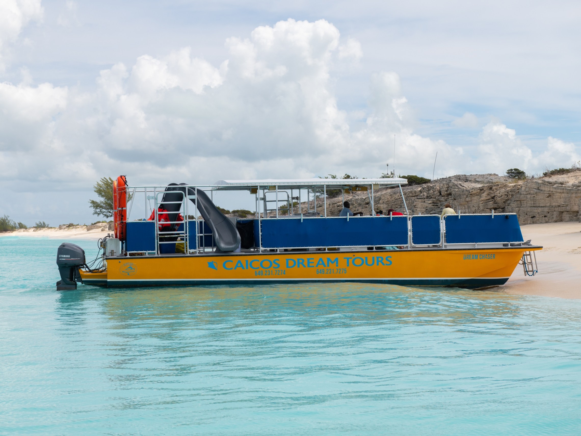 a blue and white boat sitting next to a body of water