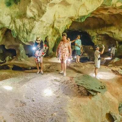 Group of people exploring a cave with flashlights and rocky walls.