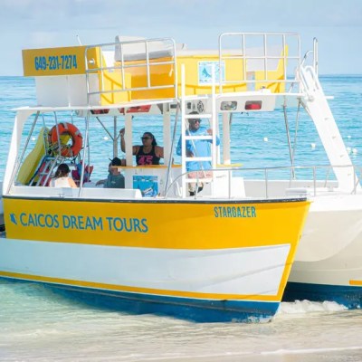 Yellow and white boat named Stargazer on turquoise water with people aboard.